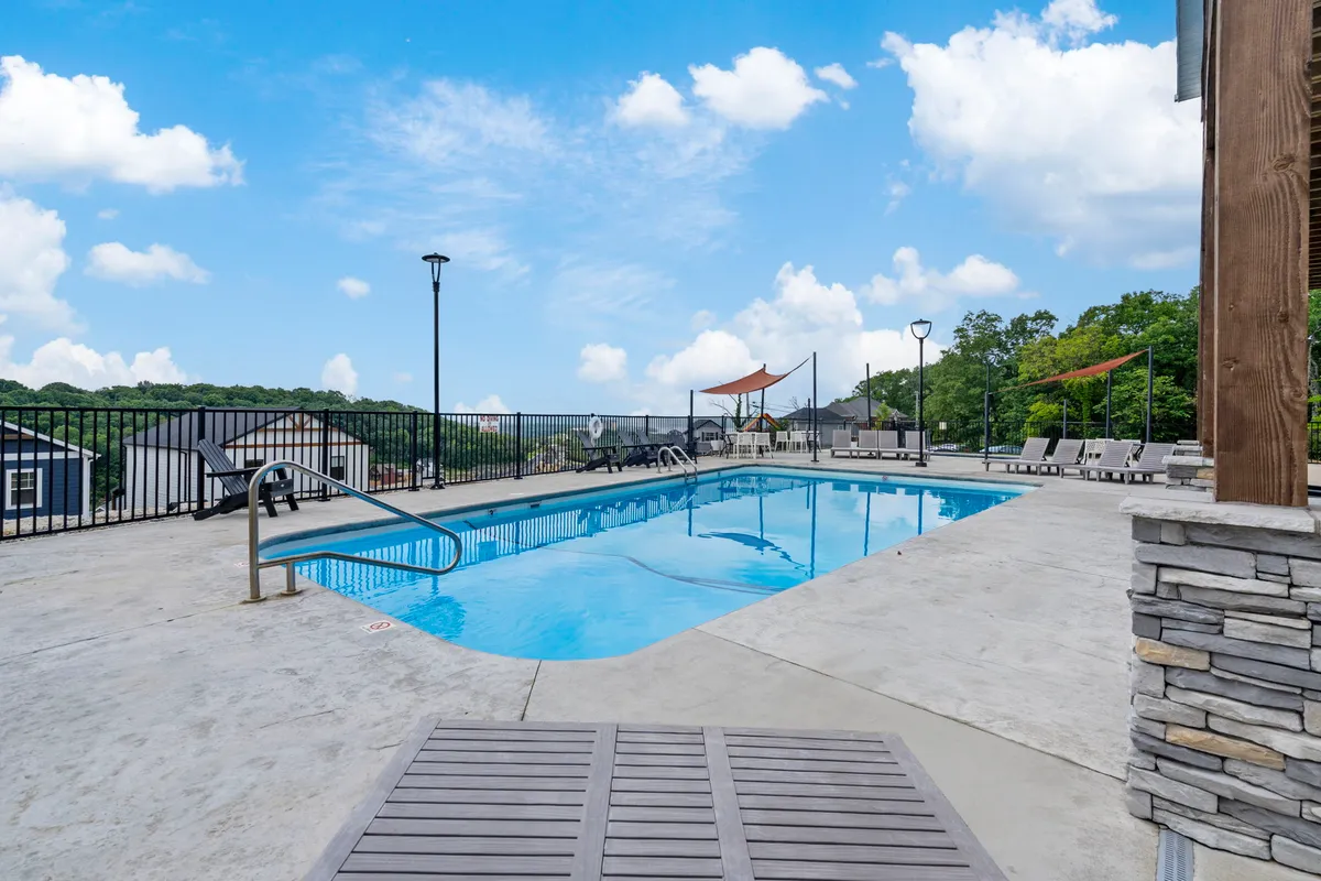 This exterior image captures a sparkling outdoor swimming pool surrounded by lounge chairs, a landscaped backdrop, and sunlit open-air relaxation areas. The mood is leisurely and inviting, suggesting a space ideal for summer fun, sunbathing, and family gatherings.