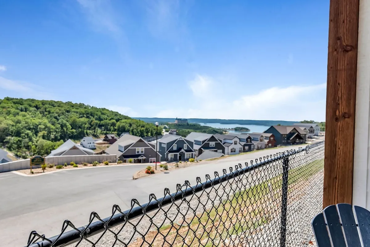 A tranquil view overlooking homes, a shimmering lake, and rolling green hills. The peaceful scene invites evening strolls or relaxing moments outside, echoing the restful vibe described post-golf.