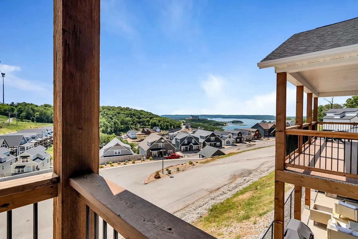 A serene view of Table Rock Lake and the surrounding hills, with neighborhood houses in the foreground. The scene suggests proximity to lakeside activities and showcases the beautiful natural setting that frames the home’s outdoor spaces.